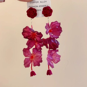 Dettaglio macro di orecchini a rosa in tessuto rosso con ago in argento S925 e lega di rame