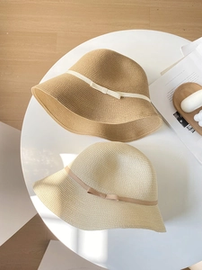 Detail of woven straw sun hats with elegant ribbon bows and wavy brims in macro view
