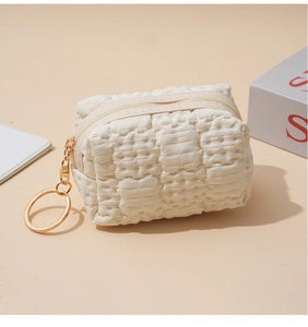 Detail of cream waffle texture coin purse with elegant gold zipper and metal ring
