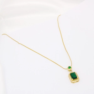 Detail of gold necklace with emerald rectangle pendant and sparkling cubic zirconia halo