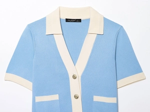 Detail of blue knit cardigan featuring contrast collar and gold relief buttons