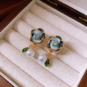 Detailed shot of vintage blue enamel flower earrings with white pearls in a wooden box