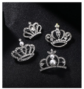 Detail view of four elegant silver crown brooches with rhinestones and pearls