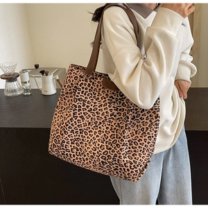 Détail d'un grand sac cabas léopard en toile avec des anses marron porté à l'épaule