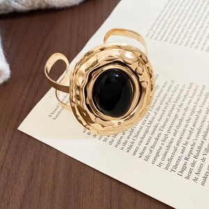 Dettaglio di un bracciale dorato martellato vintage con una grande pietra ovale in acrilico