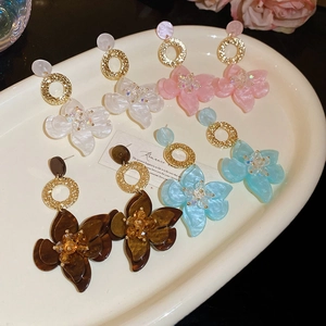 Details von Harzblumen Ohrringen mit Kristallmitte in weißer Keramikschale