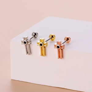 Detailed macro view of cross-shaped stainless steel earrings in silver, gold, and rose gold
