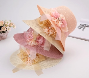 Dettaglio di quattro cappelli da sole in paglia pieghevoli con fiori e perle eleganti