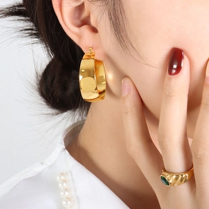 Polished 18K gold-plated hoop earrings and emerald-cut green gemstone ring set on model