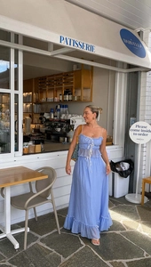 Detail of light blue summer maxi dress with multiple drawstrings and ruffle accents