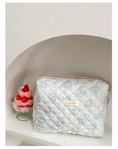 Dettaglio della borsa da trucco trapuntata a fiori con cerniera rosa e ricamo jolly