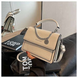 Detailed view of cream leather crossbody bag with silver chain and logo tag