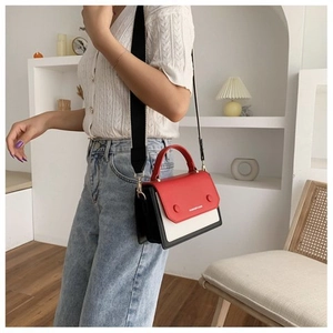 Close-up of color-block casual bag with red flap and wide black strap on model