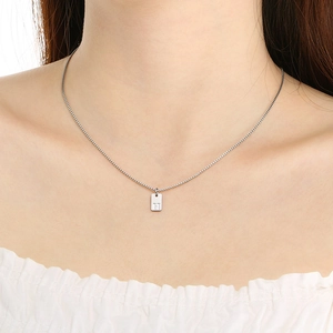Close-up of a silver box chain necklace with a rectangular pendant featuring letter H