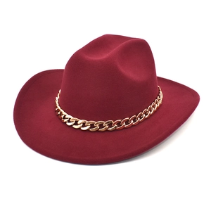 Detail of burgundy wool fedora hat featuring a chunky gold chain accessory decoration