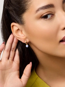 Detail of 18K gold hoop earring with blue and white porcelain bead on a model