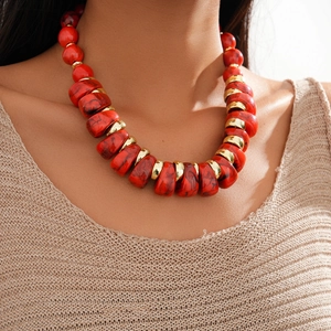 Detail of chunky red marbled resin beads and golden metallic discs on a statement necklace