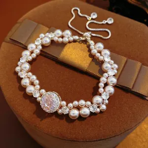 Elegant double-row pearl bracelet with a pink crystal centerpiece in a luxury gift box