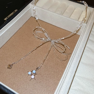 Detail of beaded bow necklace with heart pendant and light blue disc charms