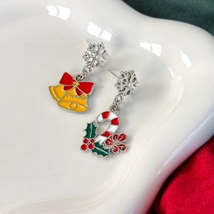 Makroansicht asymmetrischer Weihnachtsohrringe mit Schneeflocken und festlichen Anhängern