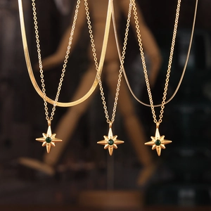 Gold layered necklaces featuring starburst pendants with green zircons in titanium steel