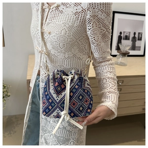 Detailed close-up of blue and white woven bucket bag with elegant cream leather drawstring