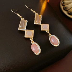 Detailed macro view of vintage gold drop earrings with pink and taupe gems and crystals