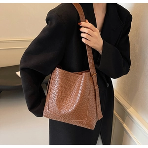 Detail of caramel brown woven texture on a vintage style faux leather tote shoulder bag