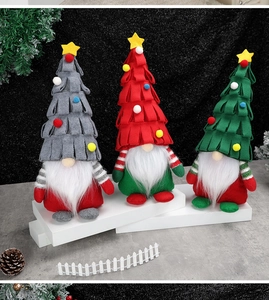 Tre gnomi natalizi in peluche grigio rosso e verde con cappelli a stella su base festiva