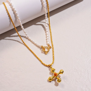 Detailed shot of double-layered necklace with freshwater pearls and a vintage gold cross pendant