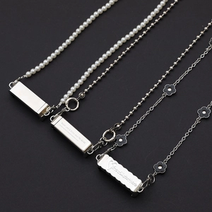 Metal crossbody phone clip chains with pearl and engraved charms on dark background