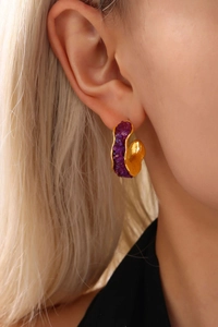 Detail of a C-shaped gold PVD plated stainless steel earring with purple crystal stones