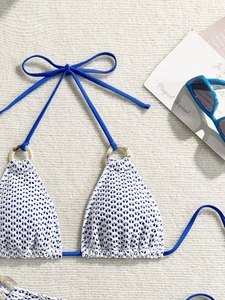 Detailed macro view of crochet bikini top with marble ring detail and blue tie straps