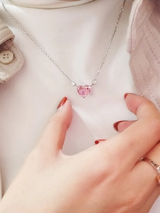 Close-up of a pink heart gemstone necklace with white diamond accents on a silver chain