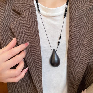 Detail of wooden gourd droplet pendant necklace on model with black beaded rope chain