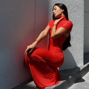Detailweergave van een rode slim-fit maxi-jurk met hoge hals en geplooide details