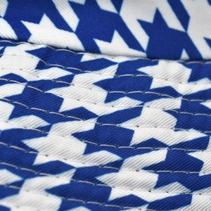 Macro detail of blue star pattern fabric and reinforced stitching on reversible bucket hat