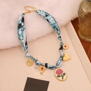 Close-up of vintage scarf necklace with rose pendants and blue tie-dye fabric details