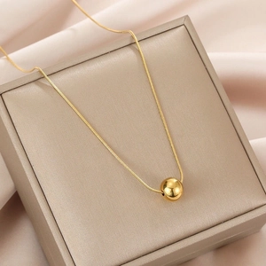 Minimalist gold titanium steel necklace with a single round bead on a silk display