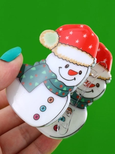 Detail view of a cute snowman hair claw clip with red hat and green scarf held by a hand