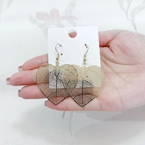 Detailed close-up of golden heart-shaped earrings with intricate leaf vein cutouts