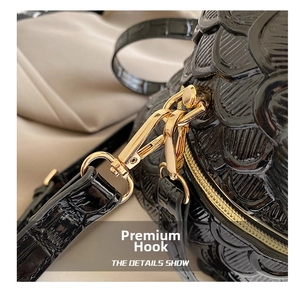 Detail of golden lobster clasp on black fish-scale embossed faux leather handbag strap