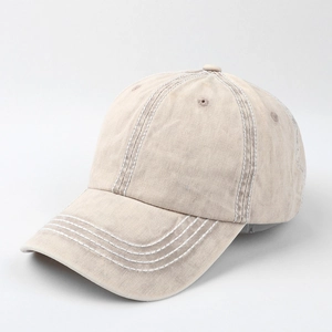 Close-up of contrast white stitching and washed cotton texture on beige baseball cap