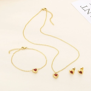 Parure de bijoux en acier inoxydable doré 18k avec pierres de cœur rouges sur tissu beige