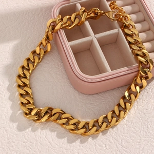 Close-up of a gold-colored chunky Cuban link chain necklace with a lobster clasp closure