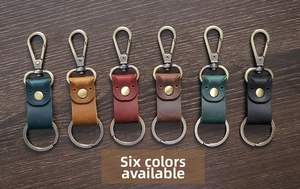 Gedetailleerd overzicht van zes vintage lederen sleutelhangers in diverse kleuren op hout