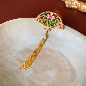 Macro shot of 18K gold plated fan brooch with enamel flowers, pearl, and long tassels
