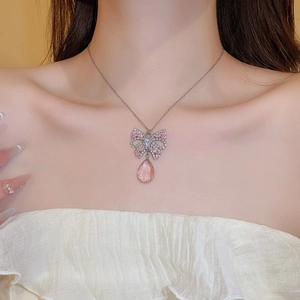 Close-up of pink butterfly and water drop pendant necklace on female model neck