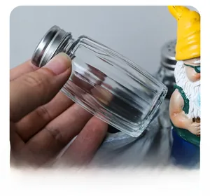 Vue détaillée d'un pot à épices en verre strié avec couvercle en métal et figurine de nain