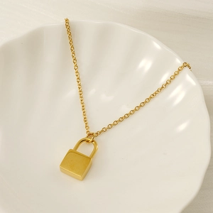 Collier avec pendentif cadenas doré présenté sur un plateau en forme de coquillage